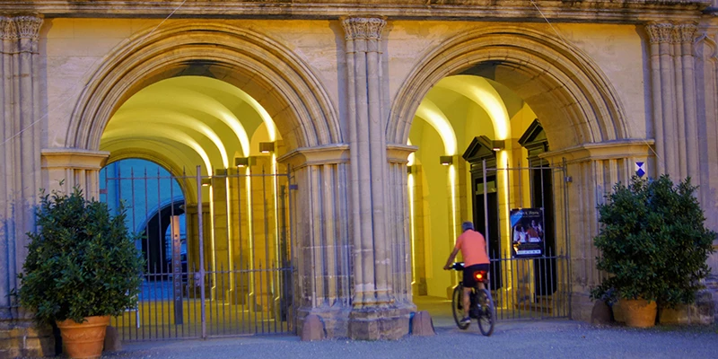 Arcaded passage near Schloss Ehrenburg lit golden at dusk, with a cyclist passing through