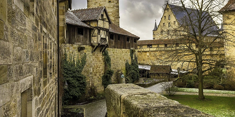 Inner courtyard of the Veste Coburg with half-timbered galleries, stone walls and a small bridge