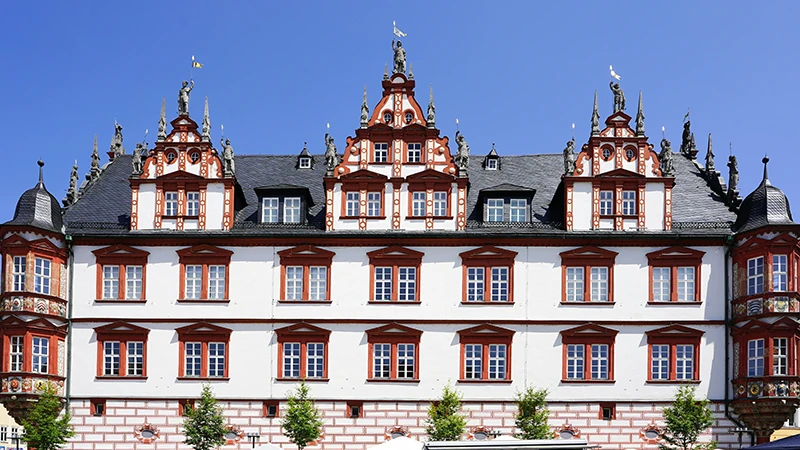 The Stadthaus in Coburg, a white facade with red-trimmed ornate gables and oriel windows