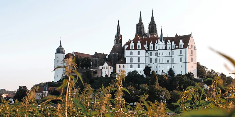 The Albrechtsburg and cathedral at dusk, their walls glowing in golden light above Meissen