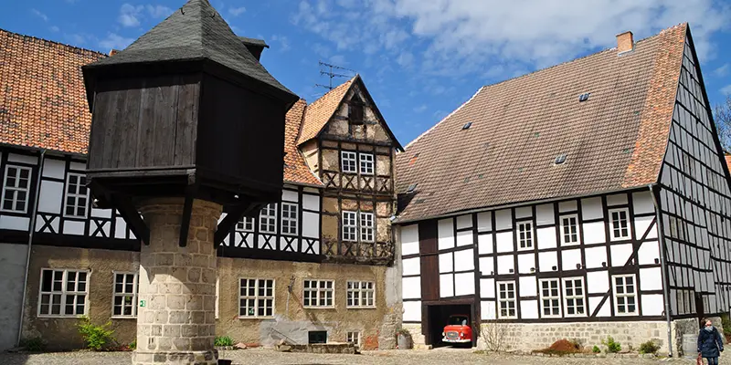 A courtyard with a projecting timber granary on a stone pillar and old farm buildings