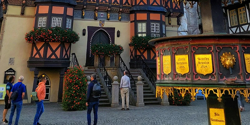 Wernigerode Town Hall and the gilded market fountain seen from below at dusk against a blue evening sky