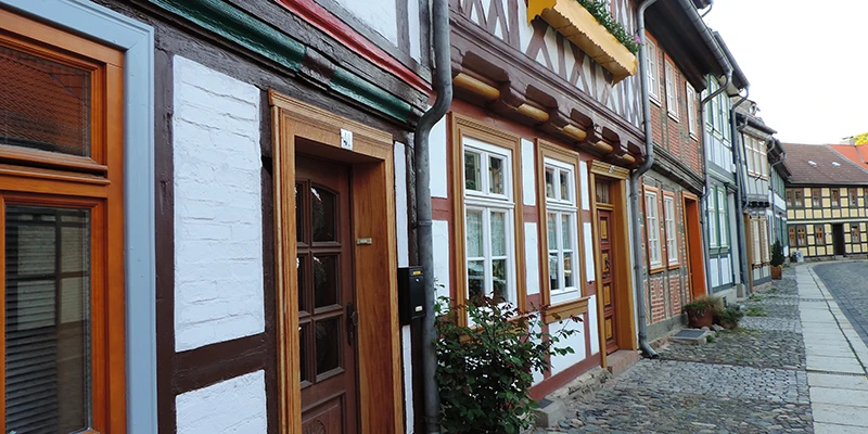 Sloping cobbled lane in Wernigerode with colourful timber-framed houses, a mailbox and a rose bush