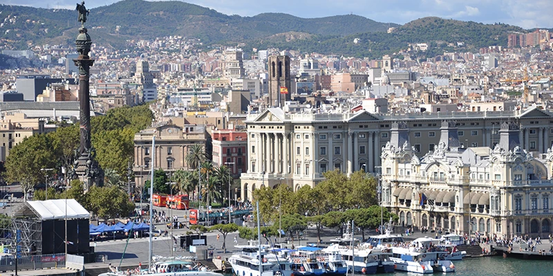 Barcelona waterfront with boats in the harbor and palm-lined promenade