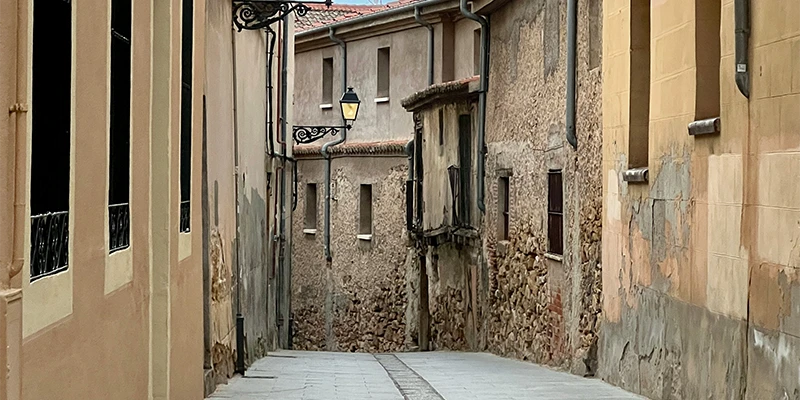 A quiet medieval side lane branching off from the main street with ancient stone buildings